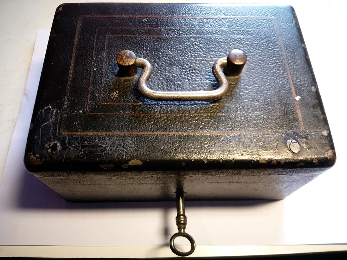An old metal money box with a key in the lock